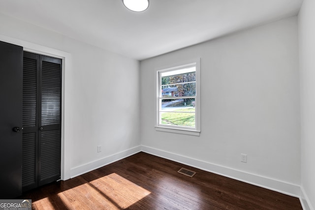 unfurnished bedroom with a closet and dark wood-type flooring