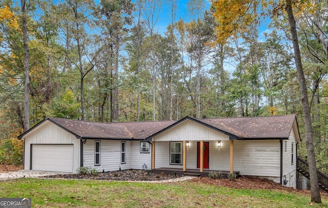 ranch-style home featuring covered porch, a front yard, and a garage