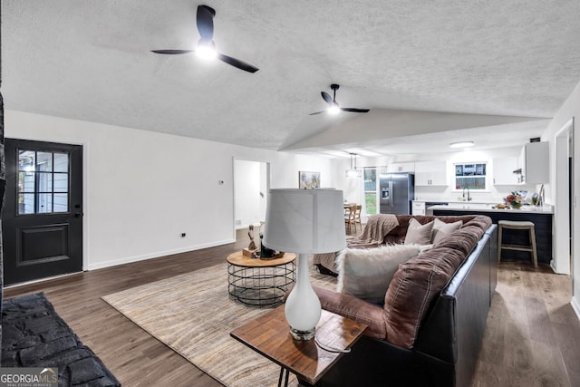 living room featuring dark hardwood / wood-style flooring, a textured ceiling, ceiling fan, sink, and lofted ceiling