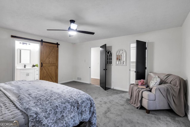 carpeted bedroom featuring connected bathroom, a barn door, and ceiling fan