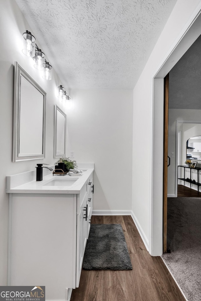 bathroom featuring vanity, wood-type flooring, and a textured ceiling