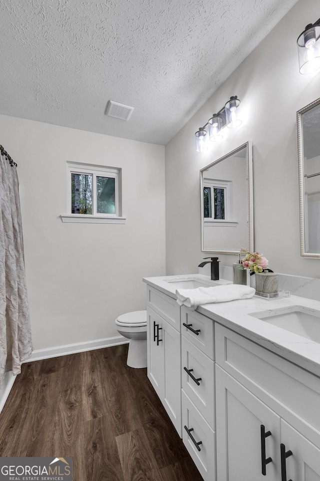 bathroom featuring vanity, hardwood / wood-style floors, a textured ceiling, and toilet