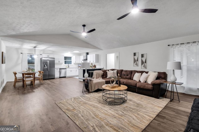 living room featuring a textured ceiling, ceiling fan, dark hardwood / wood-style flooring, and lofted ceiling