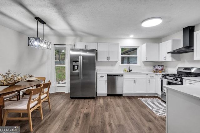 kitchen featuring white cabinets, pendant lighting, wall chimney exhaust hood, and stainless steel appliances