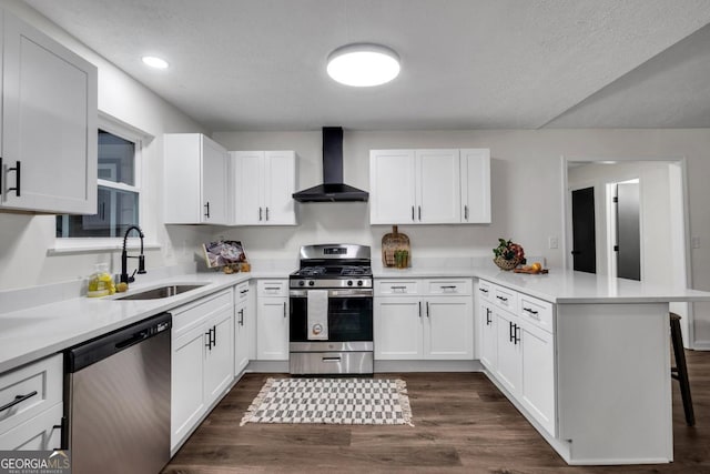 kitchen with wall chimney range hood, sink, appliances with stainless steel finishes, kitchen peninsula, and a breakfast bar area