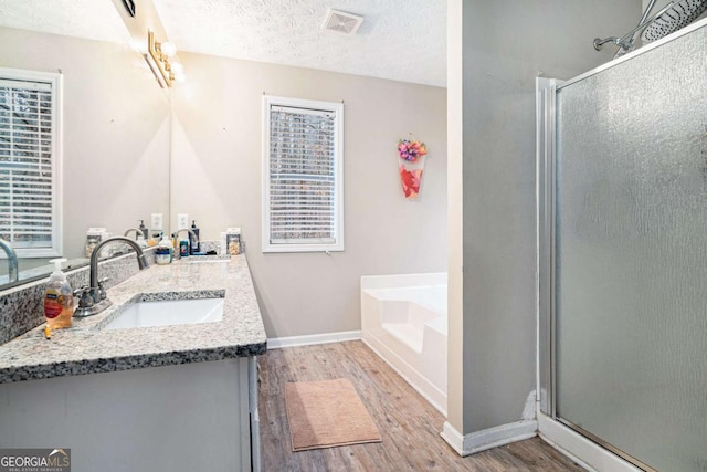 bathroom featuring vanity, a textured ceiling, hardwood / wood-style flooring, and separate shower and tub