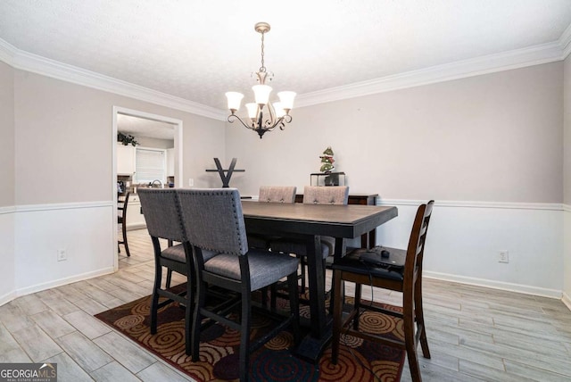 dining space with ornamental molding, a chandelier, and light wood-type flooring