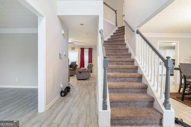 stairway featuring hardwood / wood-style floors, a textured ceiling, and crown molding