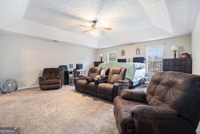 living room with carpet flooring, a textured ceiling, a raised ceiling, and ceiling fan