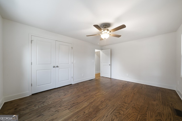 unfurnished bedroom with ceiling fan, dark hardwood / wood-style flooring, and a closet