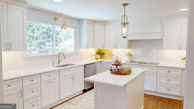 kitchen featuring stainless steel dishwasher, sink, hardwood / wood-style flooring, white cabinetry, and hanging light fixtures