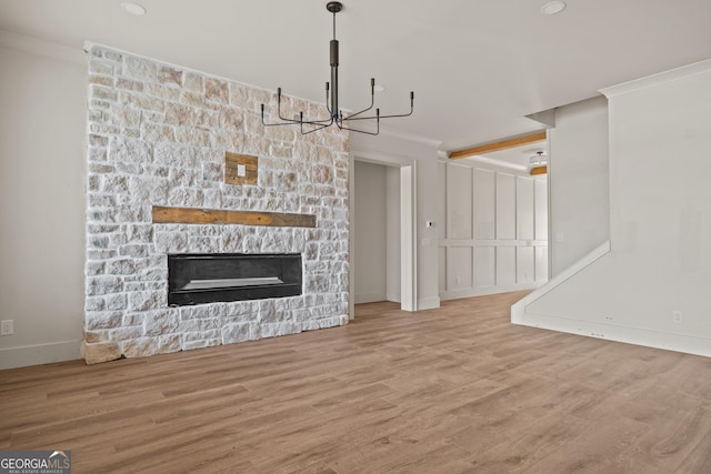 unfurnished living room featuring ornamental molding, a fireplace, and light hardwood / wood-style flooring