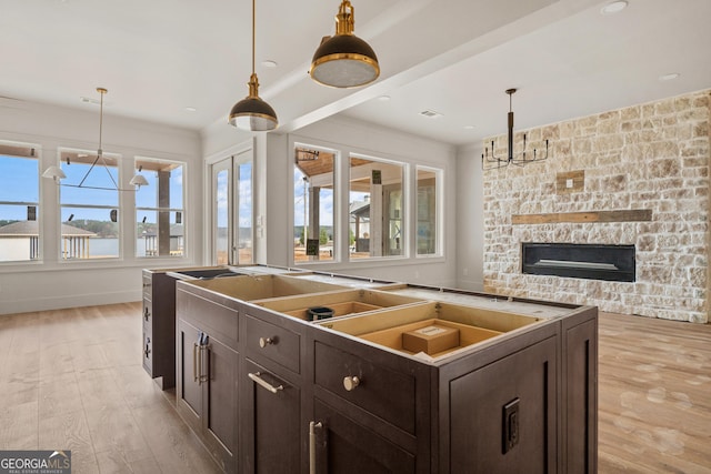 kitchen featuring a center island, a healthy amount of sunlight, dark brown cabinetry, and light hardwood / wood-style floors