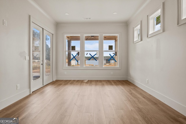 empty room featuring a wealth of natural light, light hardwood / wood-style floors, and ornamental molding