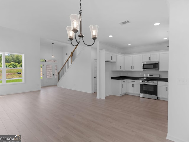 1215 White Oak Way, Griffin, GA 30224 - kitchen featuring appliances with stainless steel finishes, dark countertops, light wood finished floors, white cabinetry, and open floor plan