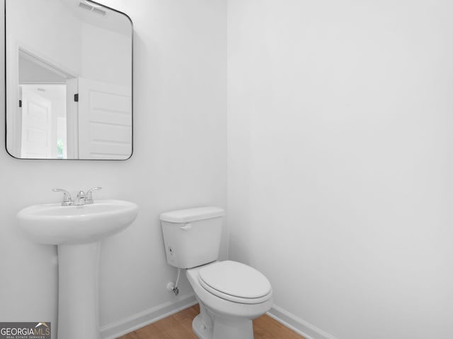 1215 White Oak Way, Griffin, GA 30224 - half bath with wood finished floors, baseboards, toilet, and a sink