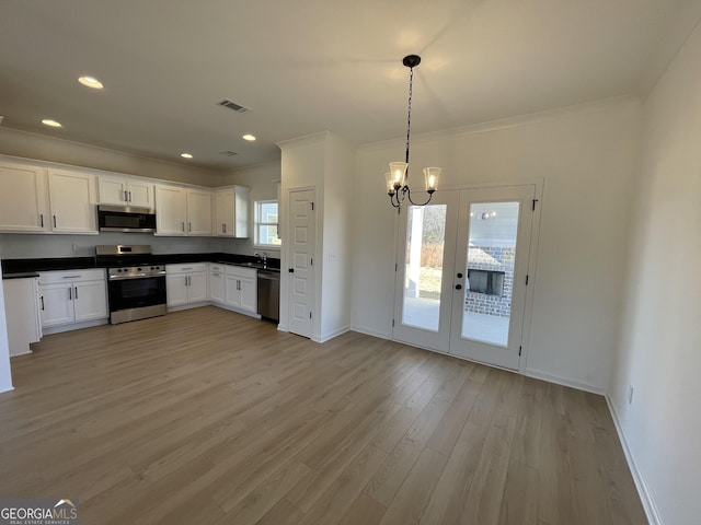 kitchen with appliances with stainless steel finishes, french doors, pendant lighting, light hardwood / wood-style flooring, and white cabinetry