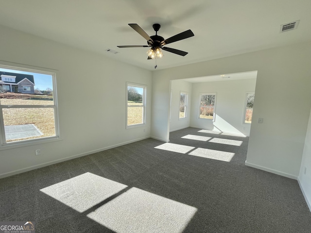 spare room featuring dark carpet and ceiling fan