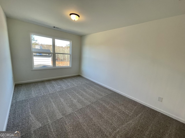 spare room with dark carpet