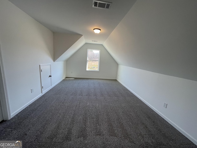 bonus room with dark carpet and lofted ceiling