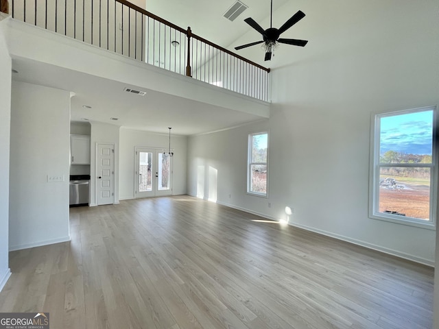 unfurnished living room featuring a high ceiling, light hardwood / wood-style flooring, french doors, and ceiling fan