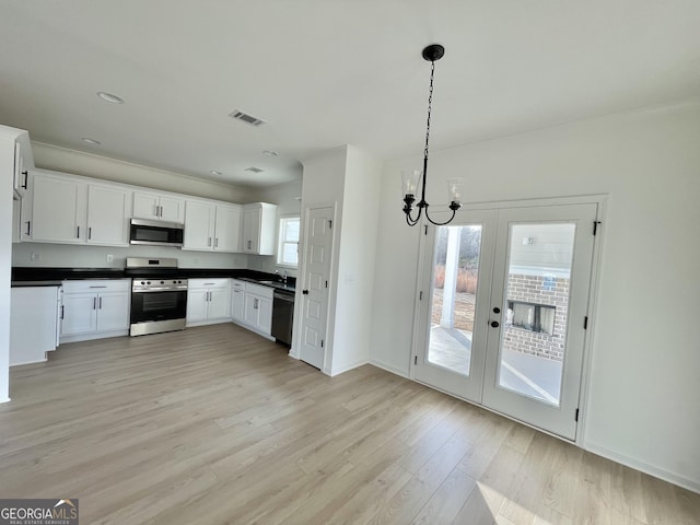 kitchen featuring french doors, stainless steel appliances, light hardwood / wood-style floors, white cabinetry, and hanging light fixtures