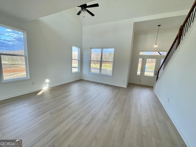 unfurnished living room featuring ceiling fan, plenty of natural light, high vaulted ceiling, and light hardwood / wood-style flooring