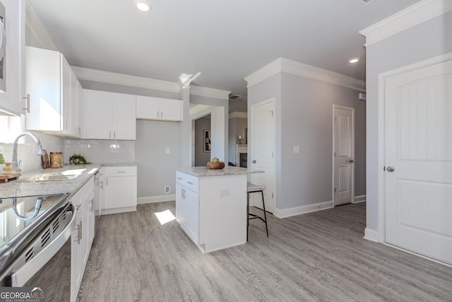 kitchen with a sink, white cabinetry, backsplash, a center island, and crown molding