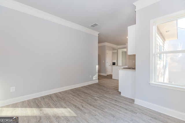 unfurnished living room with plenty of natural light, crown molding, and light hardwood / wood-style flooring