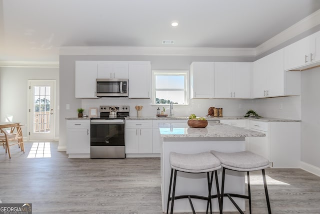 kitchen with appliances with stainless steel finishes, crown molding, and backsplash