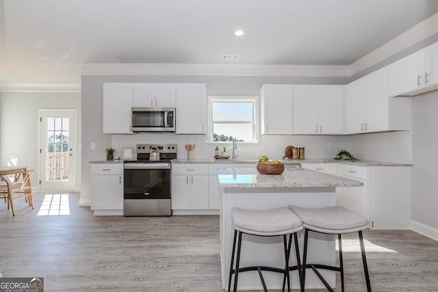 kitchen featuring appliances with stainless steel finishes, a healthy amount of sunlight, ornamental molding, and decorative backsplash