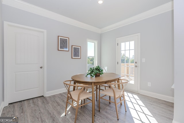 dining area featuring light wood-style flooring, baseboards, and crown molding