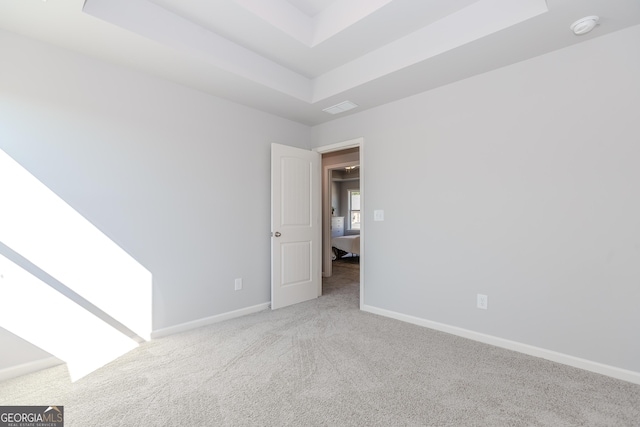 unfurnished room featuring a tray ceiling, carpet, visible vents, and baseboards