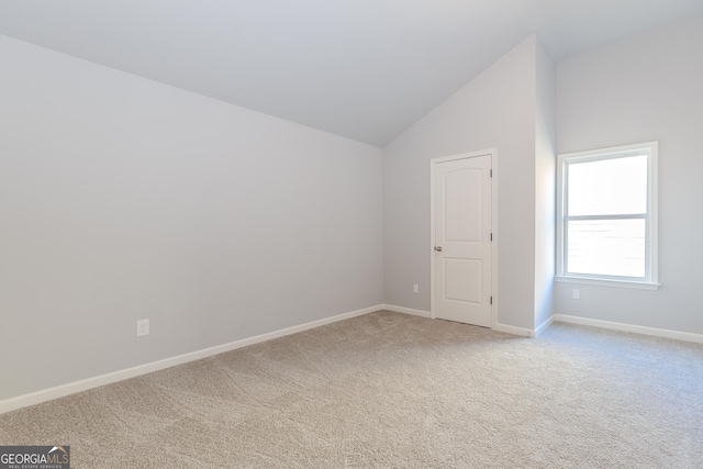 carpeted empty room with high vaulted ceiling