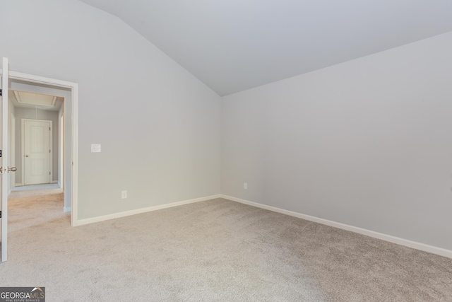 spare room with light colored carpet and vaulted ceiling