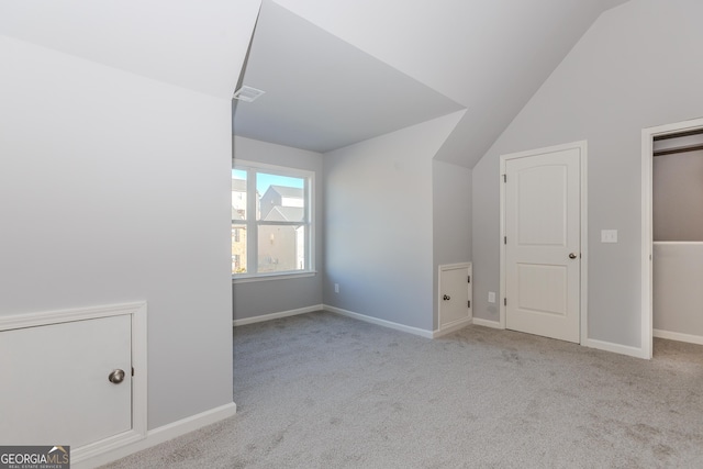 additional living space featuring light colored carpet and lofted ceiling