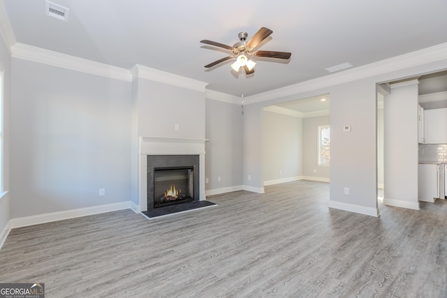 unfurnished living room with ceiling fan, crown molding, and light hardwood / wood-style floors