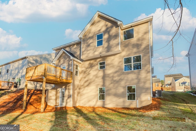 back of house with a lawn, a wooden deck, and central air condition unit