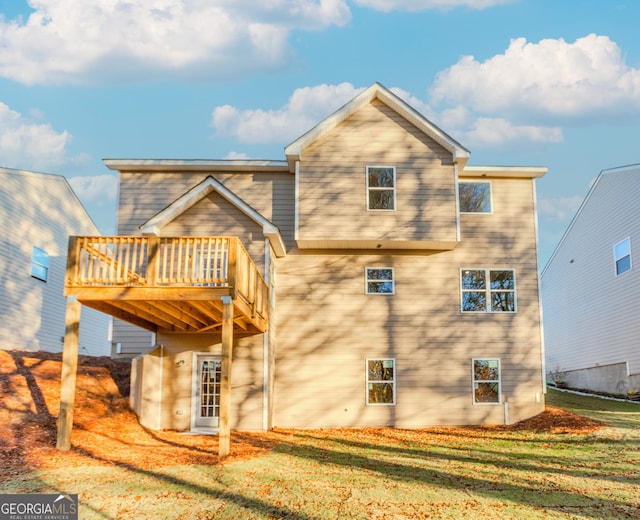 rear view of property featuring a lawn and a deck