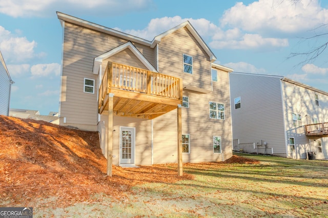 back of property featuring a wooden deck and a lawn