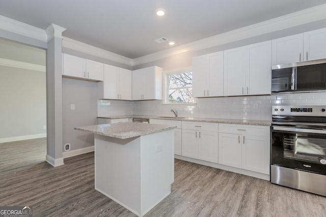 kitchen featuring light stone countertops, appliances with stainless steel finishes, a center island, and white cabinetry