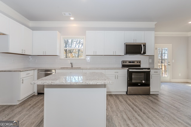 kitchen with appliances with stainless steel finishes, white cabinetry, and a kitchen island