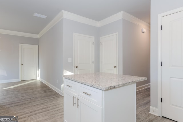 kitchen with a kitchen island, white cabinets, ornamental molding, and light wood-type flooring