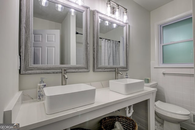 bathroom with vanity, tile walls, and toilet