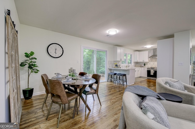 dining room featuring a barn door, light wood-type flooring, and sink