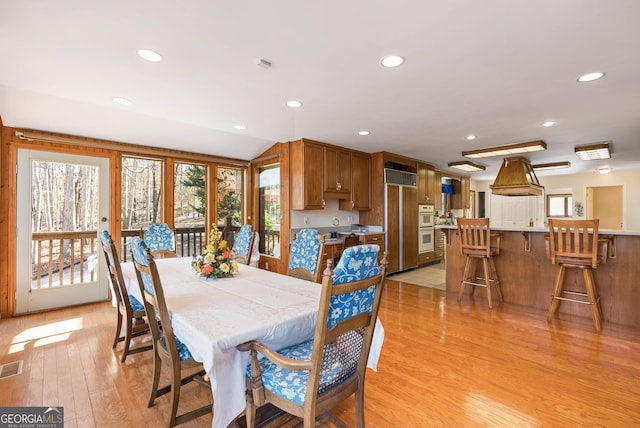 dining space featuring light wood-type flooring and lofted ceiling