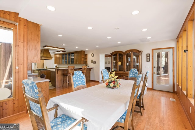 dining space with wood walls and light wood-type flooring