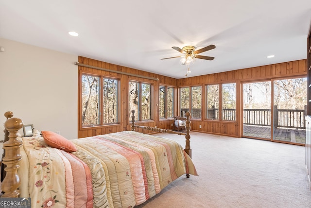 bedroom with access to exterior, ceiling fan, multiple windows, and wood walls