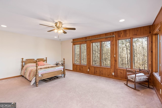 carpeted bedroom with ceiling fan and wood walls