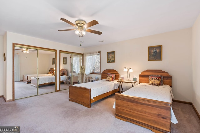 bedroom with two closets, ceiling fan, and light colored carpet